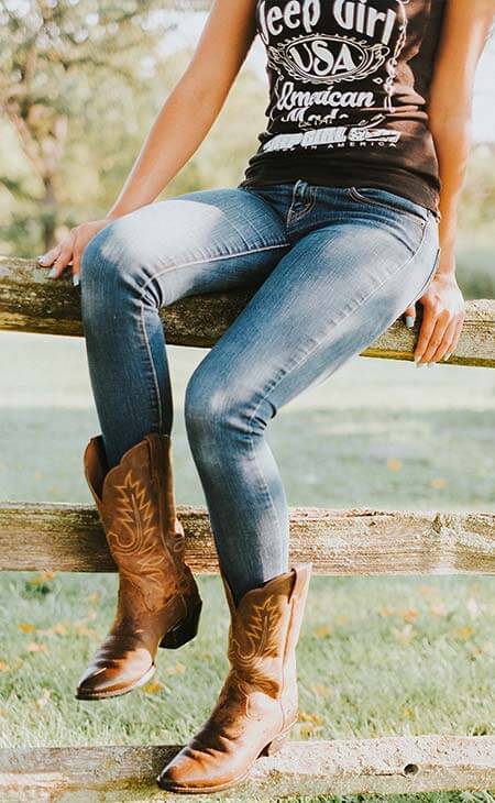 Mujer sentada valla botas cowboy