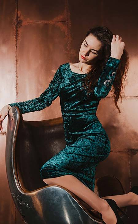 Mujer vestido terciopelo verde sentada tocando pelo