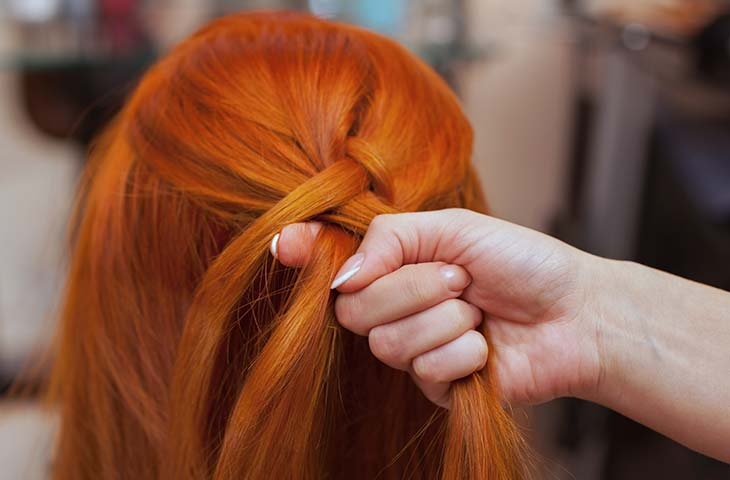 Mujer pelirroja mano trenzas