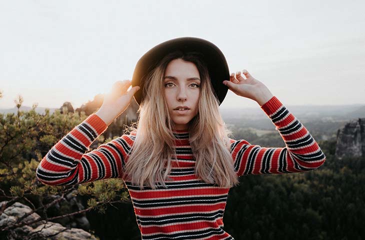 Mujer sujetando sombrero cabeza arboles