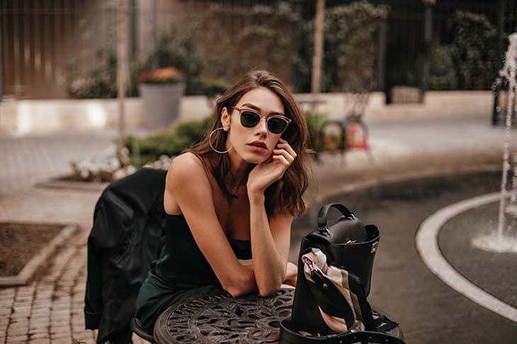 Mujer joven sentada en la calle posando con gafas de sol