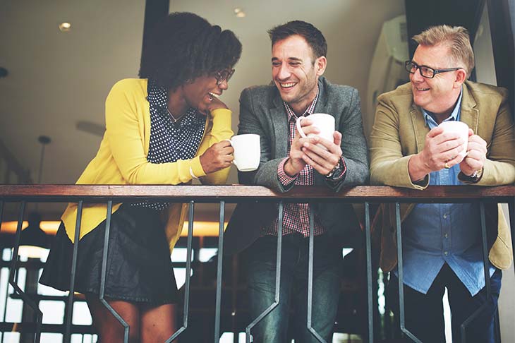 Tres trabajadores sonriendo tomando cafe