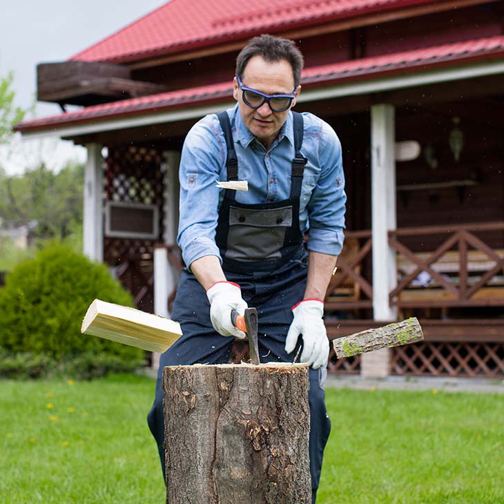 Hombre peto cortando lena jardin